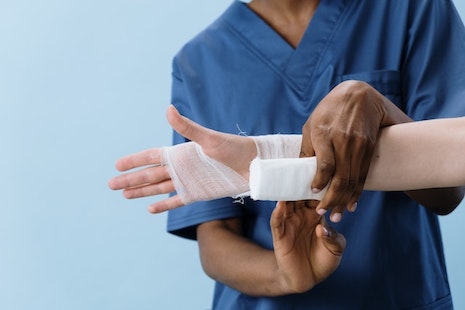 An injured hand receiving help from healthcare worker.